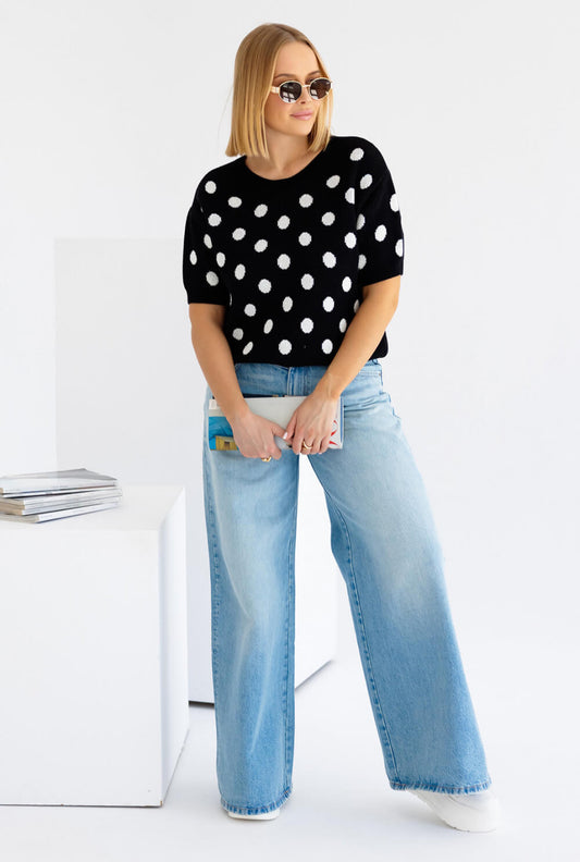 Schwarz weisser gepunkteter Strickpullover mit kurzen Ripp-Ärmeln, kombiniert mit lässiger Jeans.