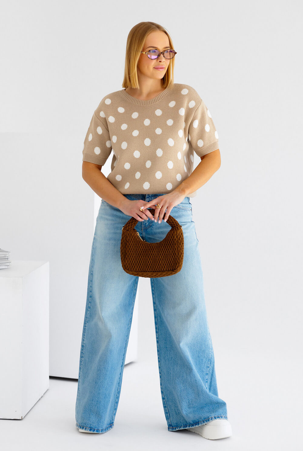 Model trägt gepunkteten Oversized Strickpullover in Beige mit Rundhalsausschnitt – Ganzkörperansicht