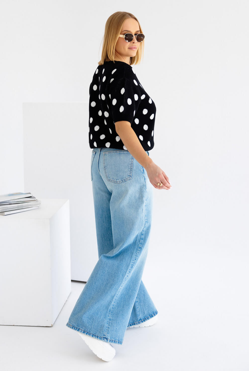 Kurzarm Strickpullover Polka Dots in Schwarz mit weißen Punkten, kombiniert mit hellen Jeans.